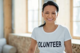 service-learning-happy-optimistic-female-volunteer-posing-blurred-background-grinning-while-gazing-camera_259150-26289
