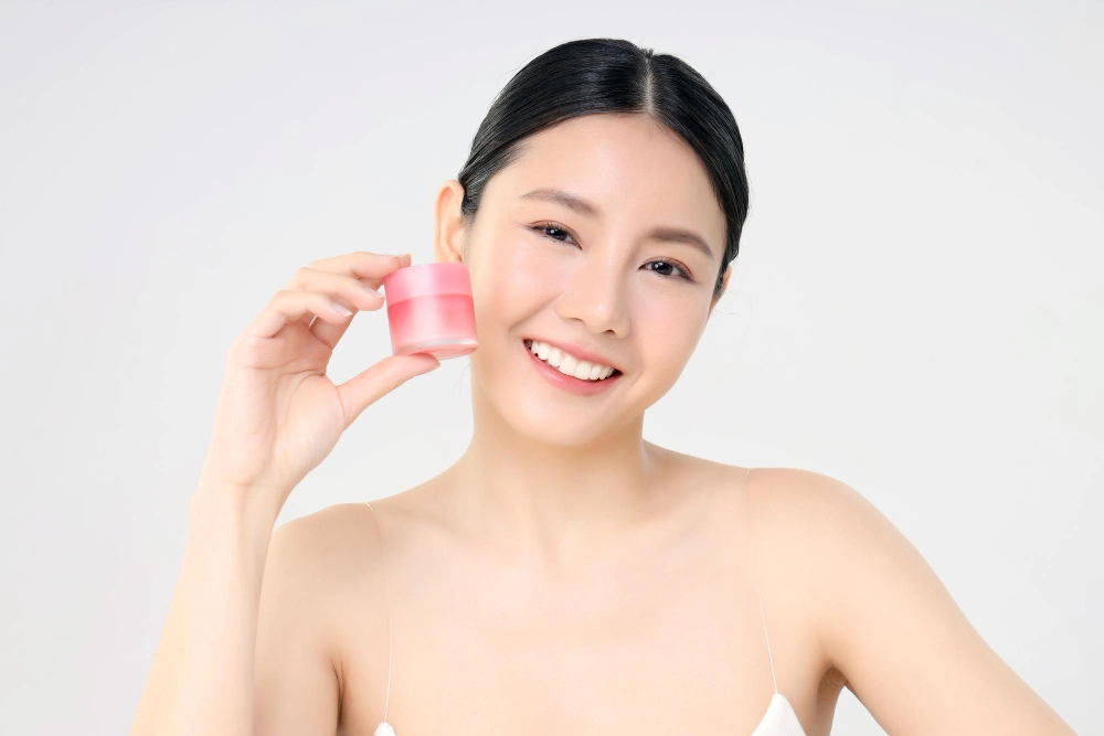 cosmetic-facial-cream-close-up-beauty-face-asian-woman-with-fresh-clean-skin-holding-facial-cream-bottle-isolated-white-beauty-skin-care-concept